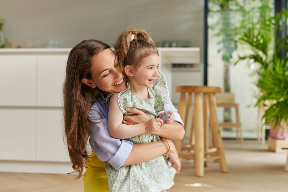 Mamá abraza a su hija pequeña en la cocina de casa
