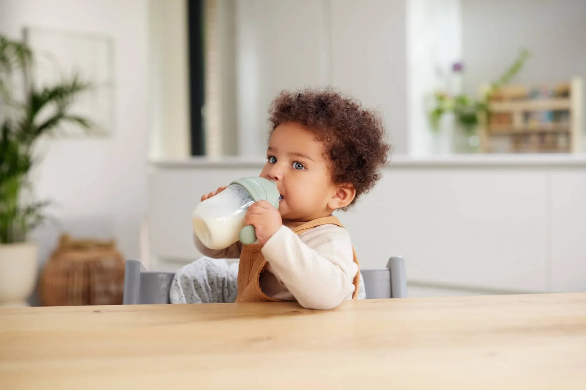 Niño pequeño tomando su leche sentado a la mesa